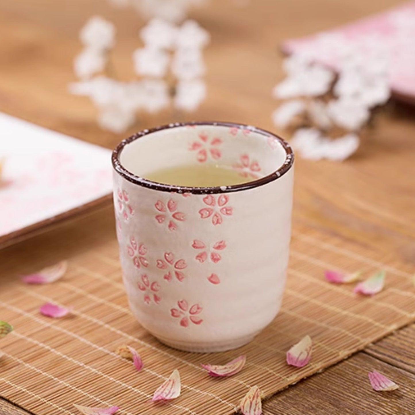 Tea cup with floral design on a wooden surface with flowers and a plate.