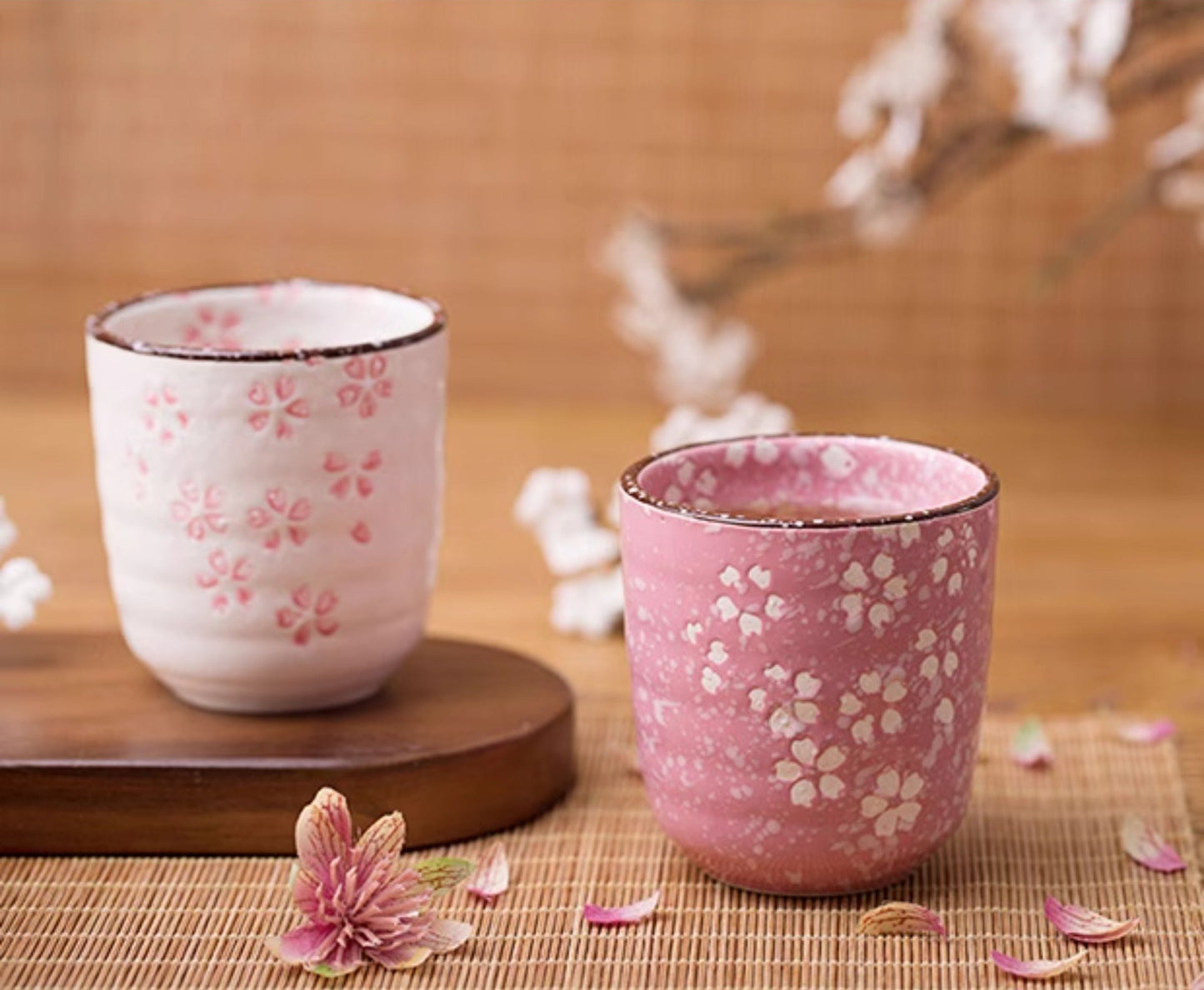 Two ceramic cups with floral patterns on a wooden surface with decorative elements.